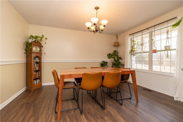 dining space featuring dark wood-type flooring and an inviting chandelier