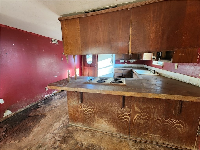 kitchen with white electric stovetop, sink, and kitchen peninsula