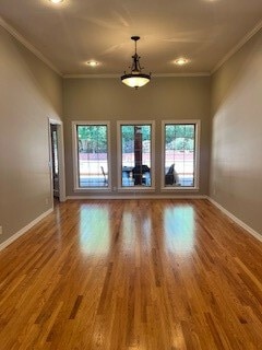 spare room with a wealth of natural light, hardwood / wood-style flooring, and crown molding