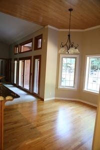 interior space featuring light wood-type flooring, ornamental molding, an inviting chandelier, and wooden ceiling