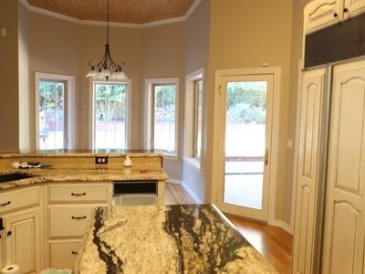 kitchen with a healthy amount of sunlight, white cabinetry, light stone counters, and decorative light fixtures