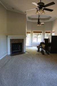 unfurnished living room featuring carpet, ceiling fan, and a raised ceiling