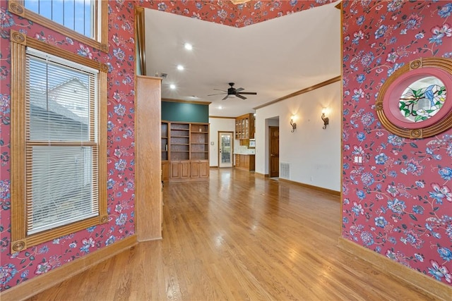 unfurnished living room with wood-type flooring, ornamental molding, and ceiling fan