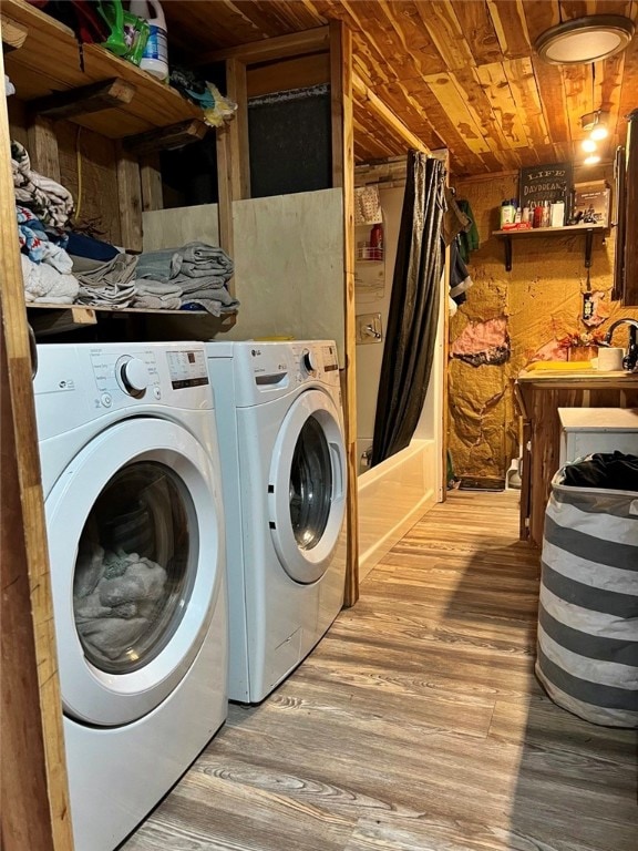 clothes washing area with washing machine and dryer, light wood-type flooring, and wooden ceiling