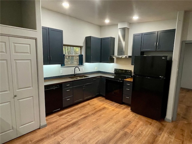 kitchen with light hardwood / wood-style floors, sink, black appliances, and wall chimney exhaust hood