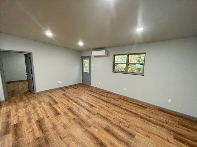 basement with light wood-type flooring and a wall mounted AC