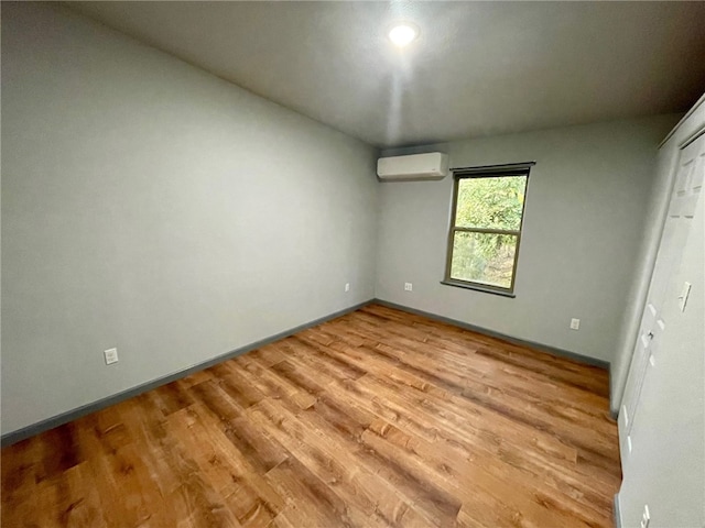 unfurnished bedroom with light wood-type flooring and a wall mounted air conditioner