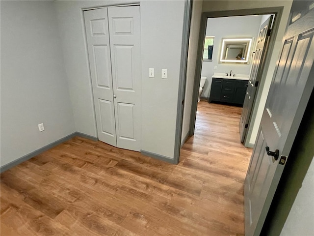 unfurnished bedroom with a closet, ensuite bathroom, and light hardwood / wood-style flooring