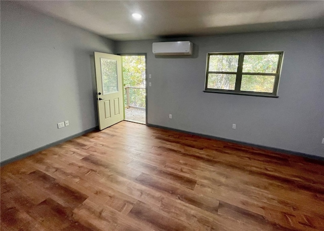 spare room featuring a healthy amount of sunlight, light hardwood / wood-style flooring, and a wall unit AC