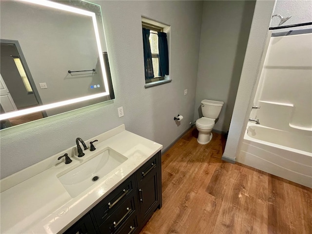 full bathroom with washtub / shower combination, toilet, wood-type flooring, and vanity