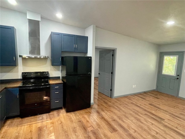 kitchen with light hardwood / wood-style floors, black appliances, and wall chimney exhaust hood