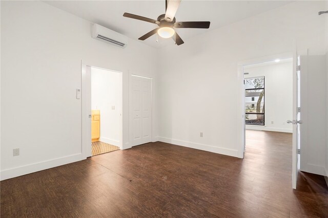 empty room with dark hardwood / wood-style floors, a wall mounted AC, and ceiling fan