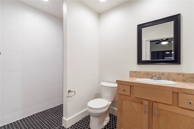 bathroom featuring vanity, toilet, a tile shower, and tile patterned flooring