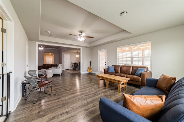 living room featuring ceiling fan, a raised ceiling, and dark hardwood / wood-style flooring