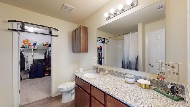 bathroom with walk in shower, hardwood / wood-style floors, vanity, and toilet