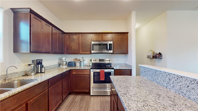 kitchen featuring light stone countertops, stainless steel appliances, light hardwood / wood-style flooring, and sink