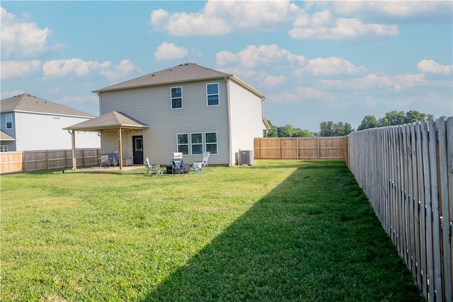 back of property with a yard and central AC