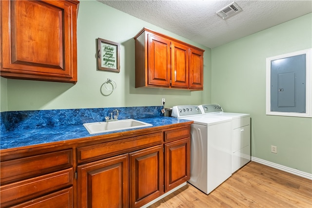 washroom featuring separate washer and dryer, sink, light hardwood / wood-style floors, electric panel, and a textured ceiling