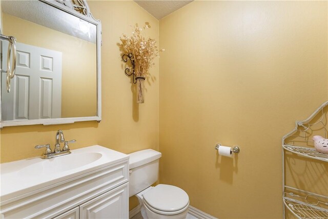 bathroom with vanity, toilet, and a textured ceiling