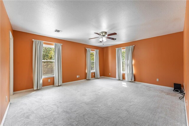 unfurnished room featuring ceiling fan, a wealth of natural light, and a textured ceiling