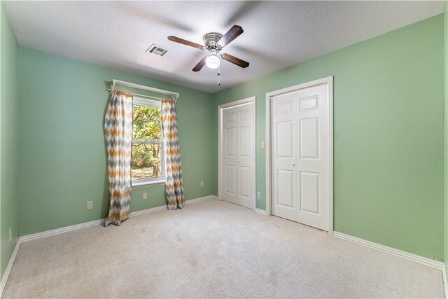 unfurnished bedroom featuring light carpet, ceiling fan, and a textured ceiling