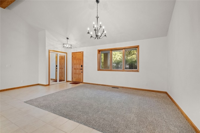 empty room featuring light colored carpet, a notable chandelier, and vaulted ceiling