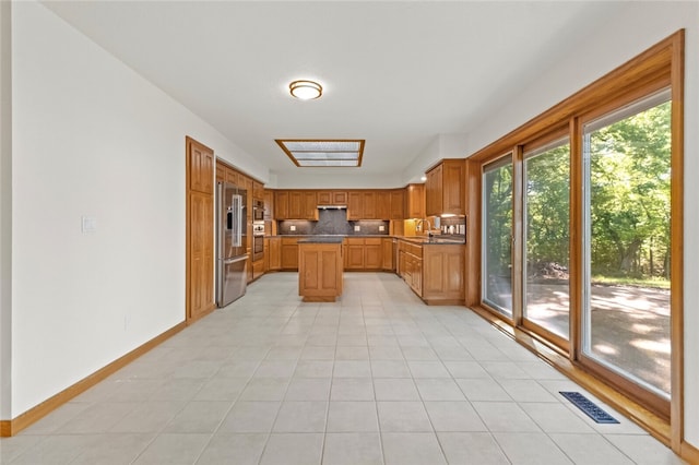 kitchen featuring light tile patterned flooring, a kitchen island, high end fridge, and a wealth of natural light