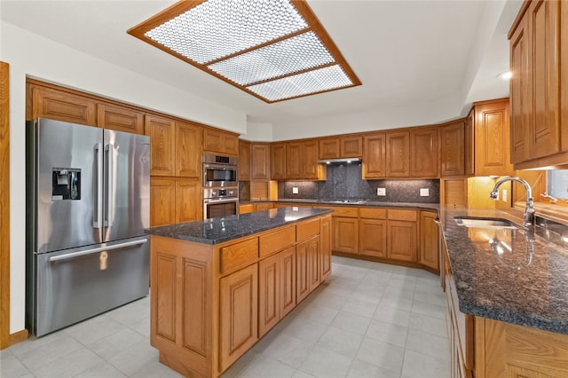 kitchen with stainless steel appliances, dark stone counters, sink, and a center island