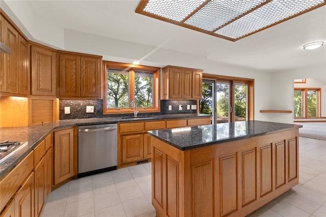 kitchen with a center island, stainless steel dishwasher, sink, decorative backsplash, and light tile patterned floors