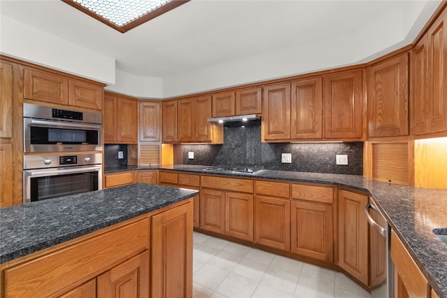 kitchen featuring appliances with stainless steel finishes, dark stone counters, and tasteful backsplash