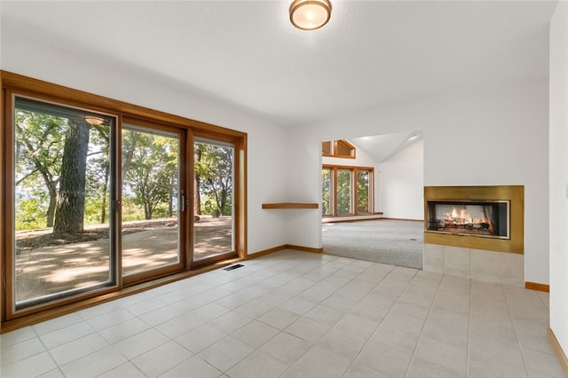 unfurnished living room featuring light tile patterned flooring, vaulted ceiling, and a wealth of natural light