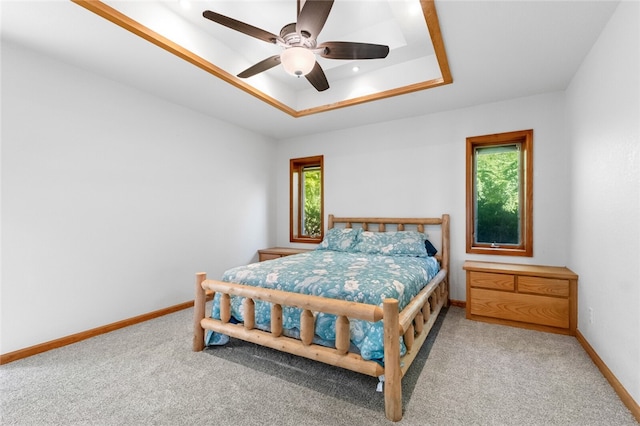 carpeted bedroom featuring a raised ceiling and ceiling fan