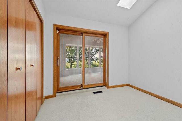 doorway to outside with lofted ceiling with skylight and light carpet