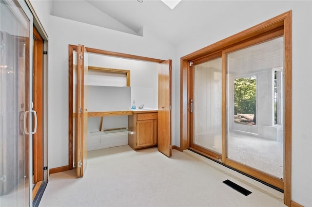 interior space featuring vaulted ceiling, sink, and light carpet