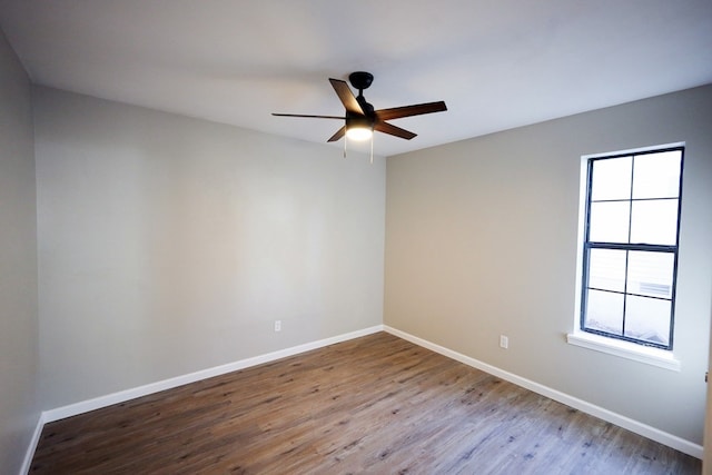 spare room featuring ceiling fan, hardwood / wood-style floors, and a healthy amount of sunlight