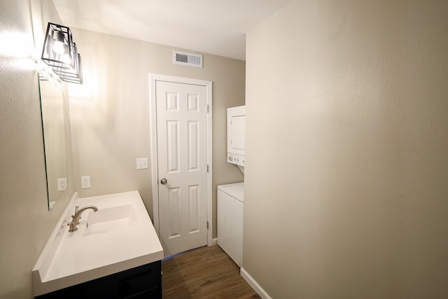 bathroom with hardwood / wood-style floors, vanity, and stacked washer and clothes dryer