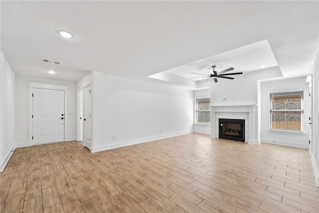 4206 SW Adams St, Bentonville, AR 72713 - unfurnished living room with a tray ceiling, a ceiling fan, a fireplace, baseboards, and light wood-style flooring