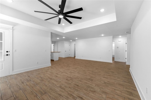 4206 SW Adams St, Bentonville, AR 72713 - unfurnished living room featuring a ceiling fan, recessed lighting, wood finished floors, baseboards, and a tray ceiling