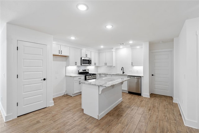 4206 SW Adams St, Bentonville, AR 72713 - kitchen with stainless steel appliances, a sink, white cabinets, light wood-style floors, and recessed lighting