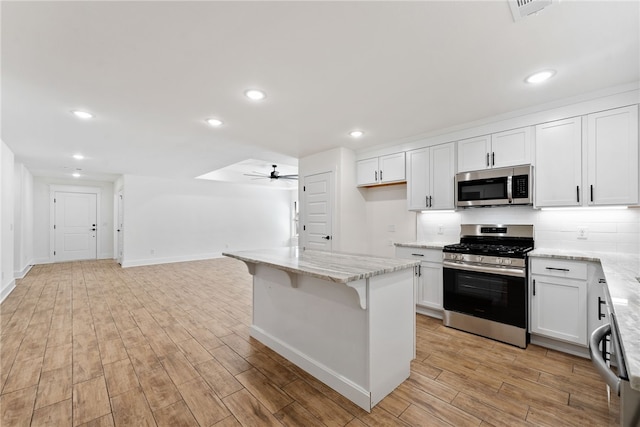 4206 SW Adams St, Bentonville, AR 72713 - kitchen with stainless steel appliances, ceiling fan, light wood-style flooring, light stone counters, and white cabinetry