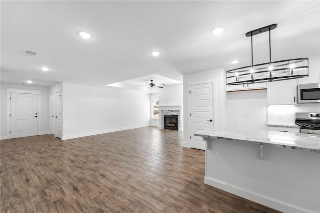 kitchen with a fireplace, decorative light fixtures, a breakfast bar area, white cabinets, and stainless steel appliances