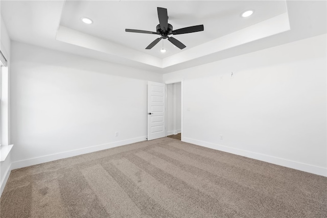 spare room with carpet floors, ceiling fan, and a tray ceiling