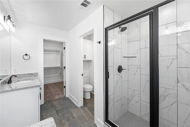 bathroom featuring hardwood / wood-style flooring, vanity, toilet, and a shower with door