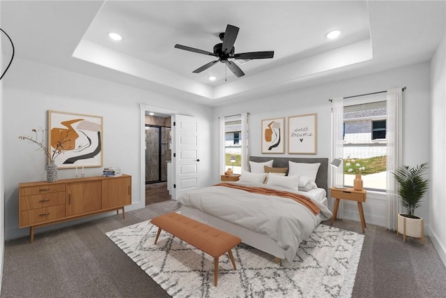 carpeted bedroom with a raised ceiling, ceiling fan, and multiple windows