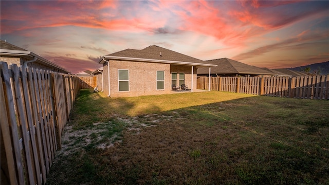 back house at dusk featuring a yard