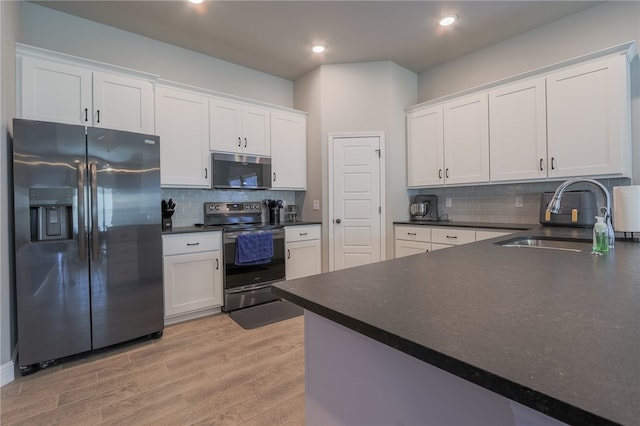 kitchen featuring light wood-type flooring, tasteful backsplash, sink, white cabinets, and appliances with stainless steel finishes