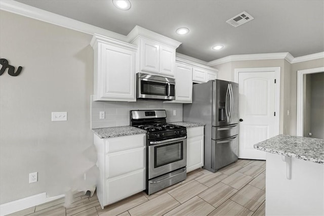 kitchen with light stone countertops, stainless steel appliances, decorative backsplash, white cabinets, and ornamental molding