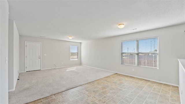 carpeted empty room featuring a textured ceiling