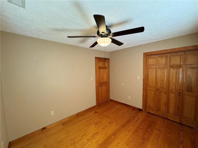 unfurnished bedroom with a closet, light hardwood / wood-style floors, a textured ceiling, and ceiling fan