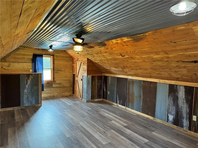 bonus room featuring ceiling fan, wood walls, wood-type flooring, wooden ceiling, and vaulted ceiling